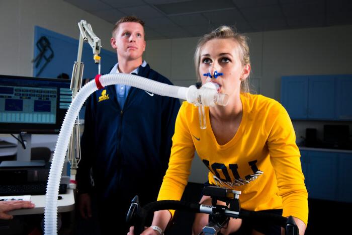 Young lady on exercise bike with ventilator tube measuring oxygen levels.