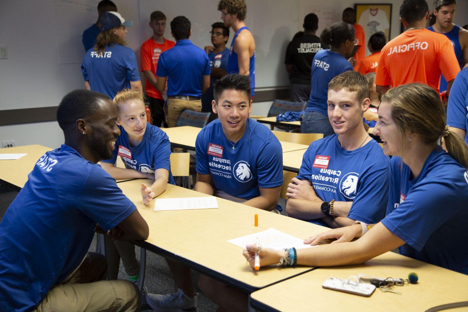 Campus Recreation employees sitting on a table smiling. 