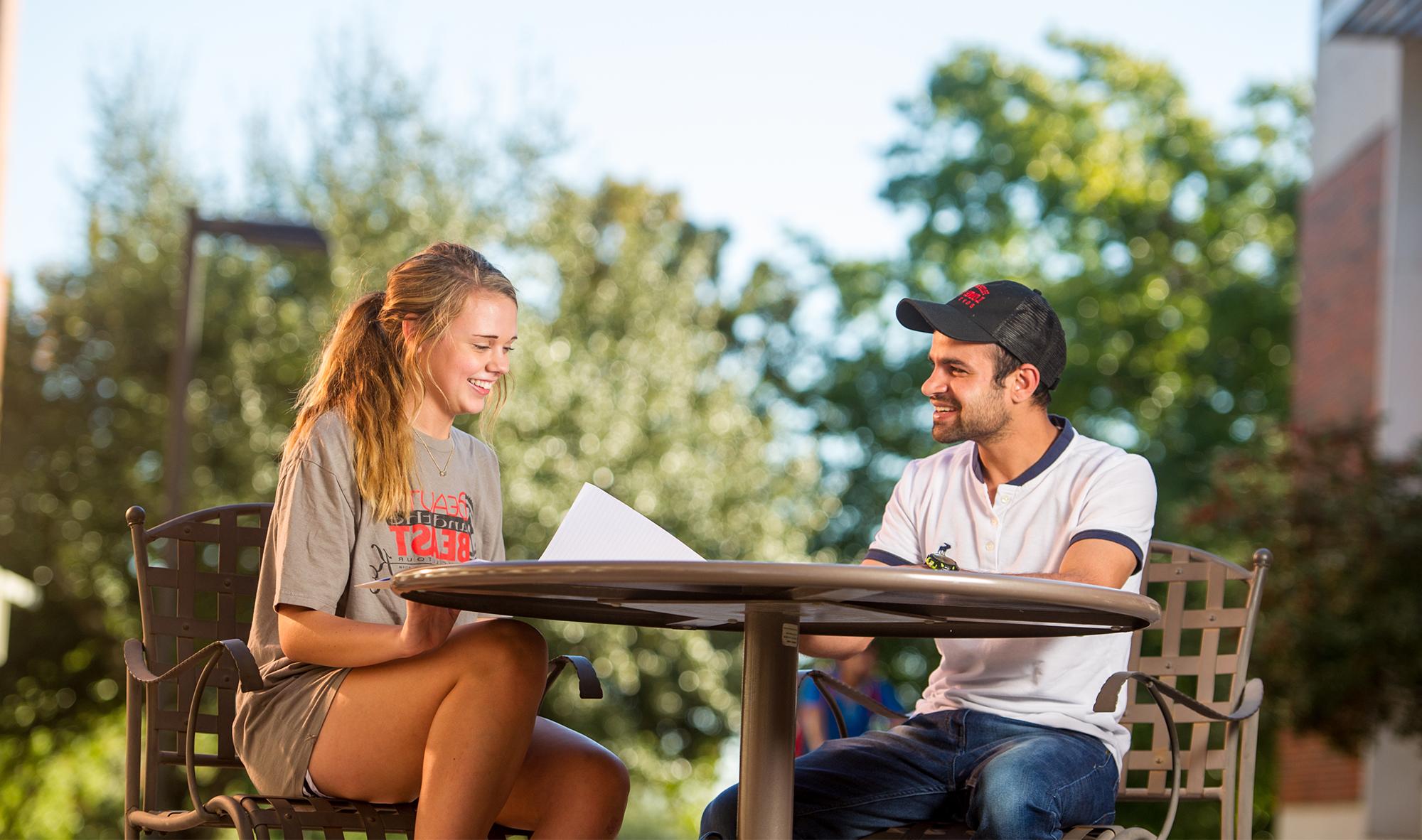 A female and male sitting at a table studying for a class.